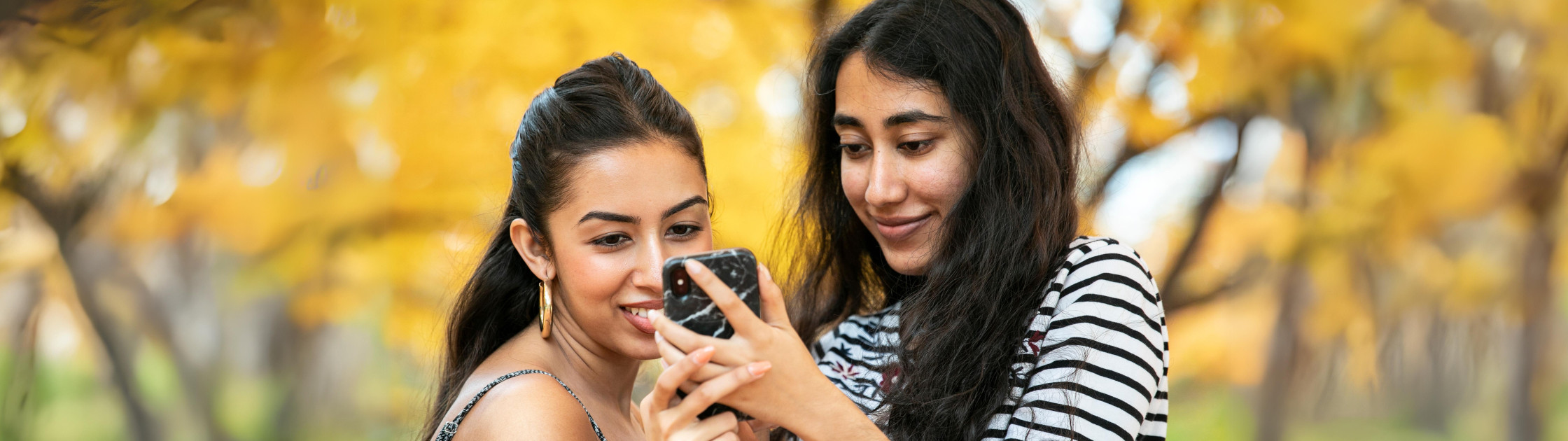 Photo of two students looking at a phone together